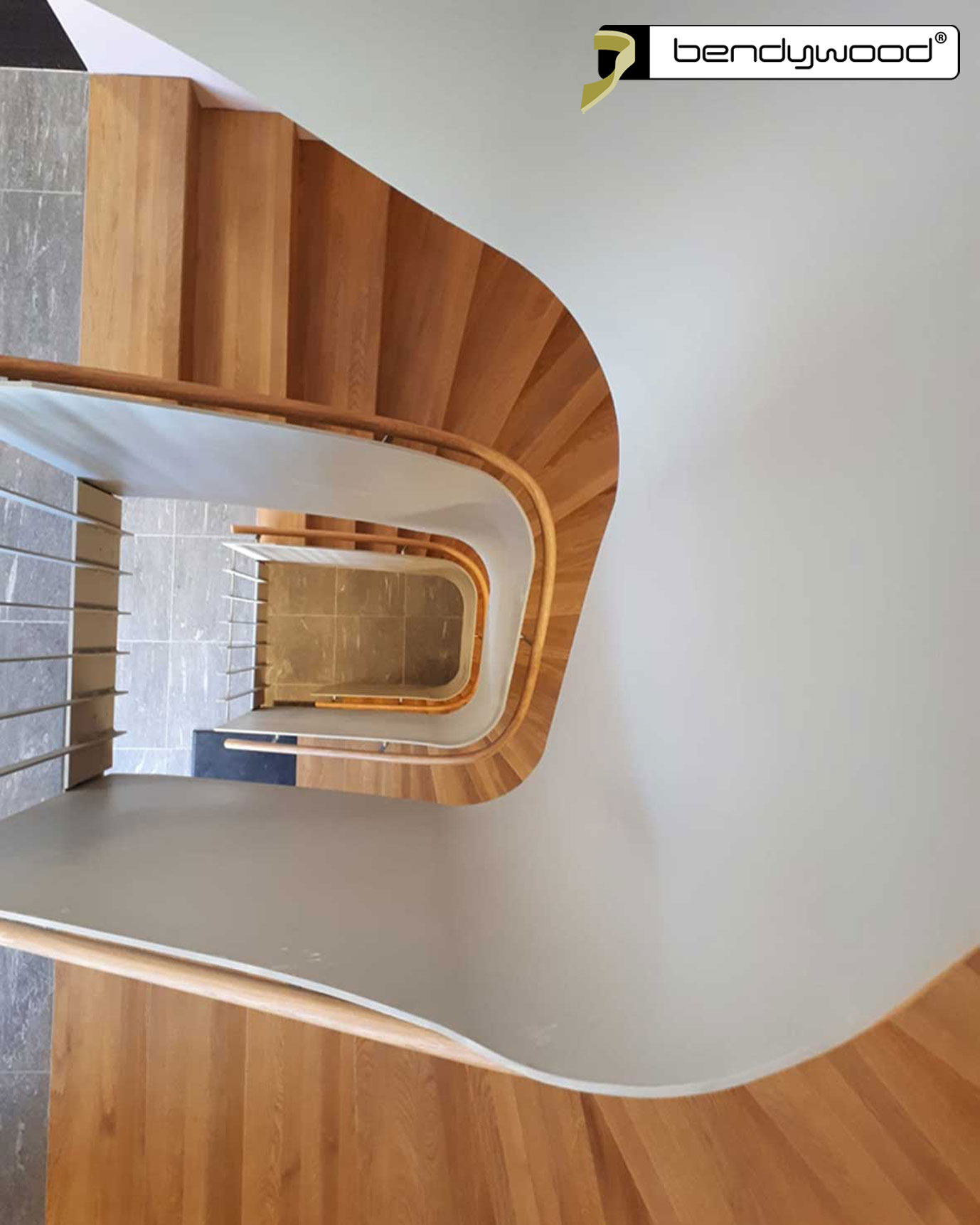Round bending handrails in Bendywood®-oak fitted on a 10 mm thick curved steel plate stair railing.